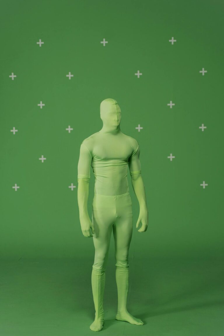 Person wearing a green chromakey suit standing in a studio setup for visual effects.